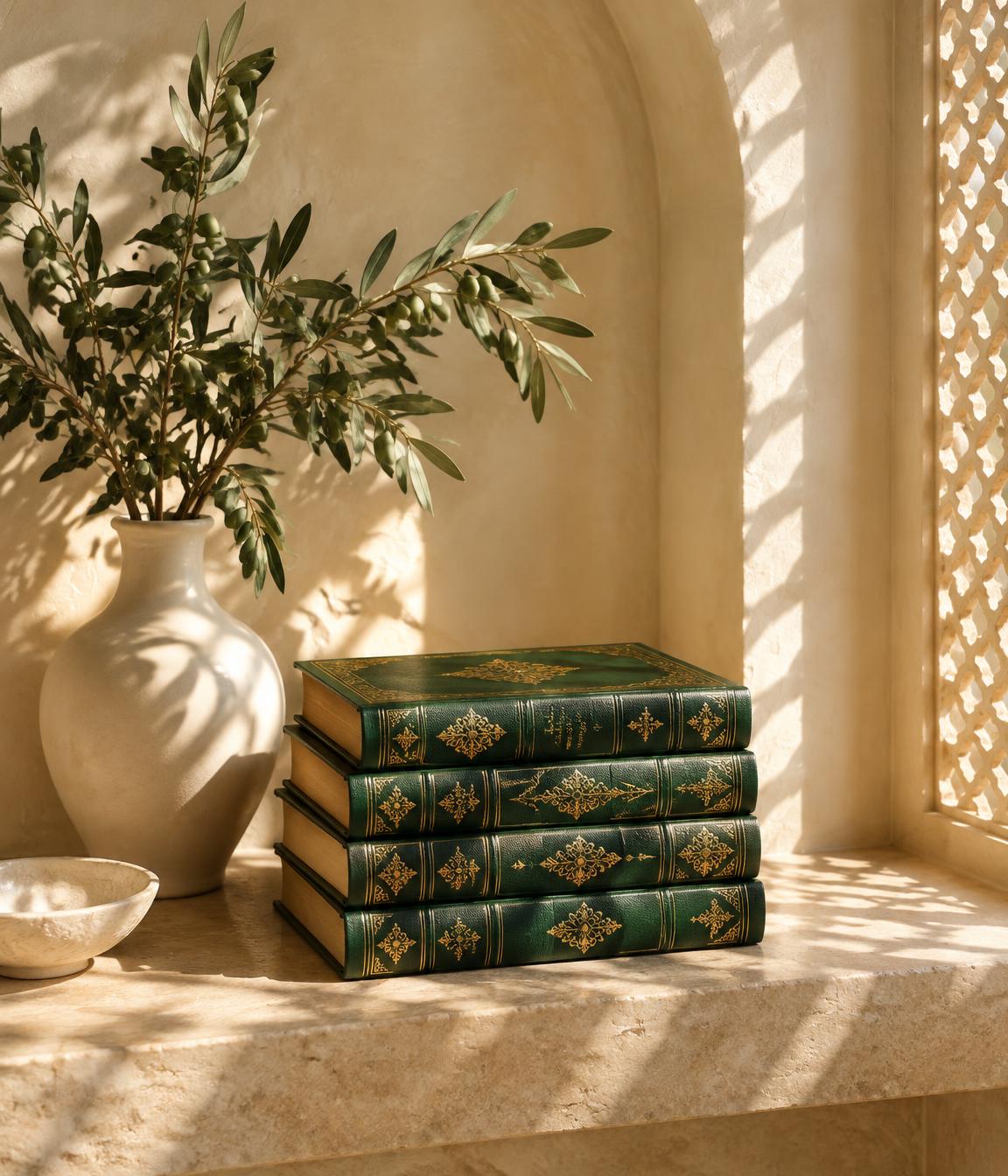 Green bound books beside an olive branch in a sunlit alcove
